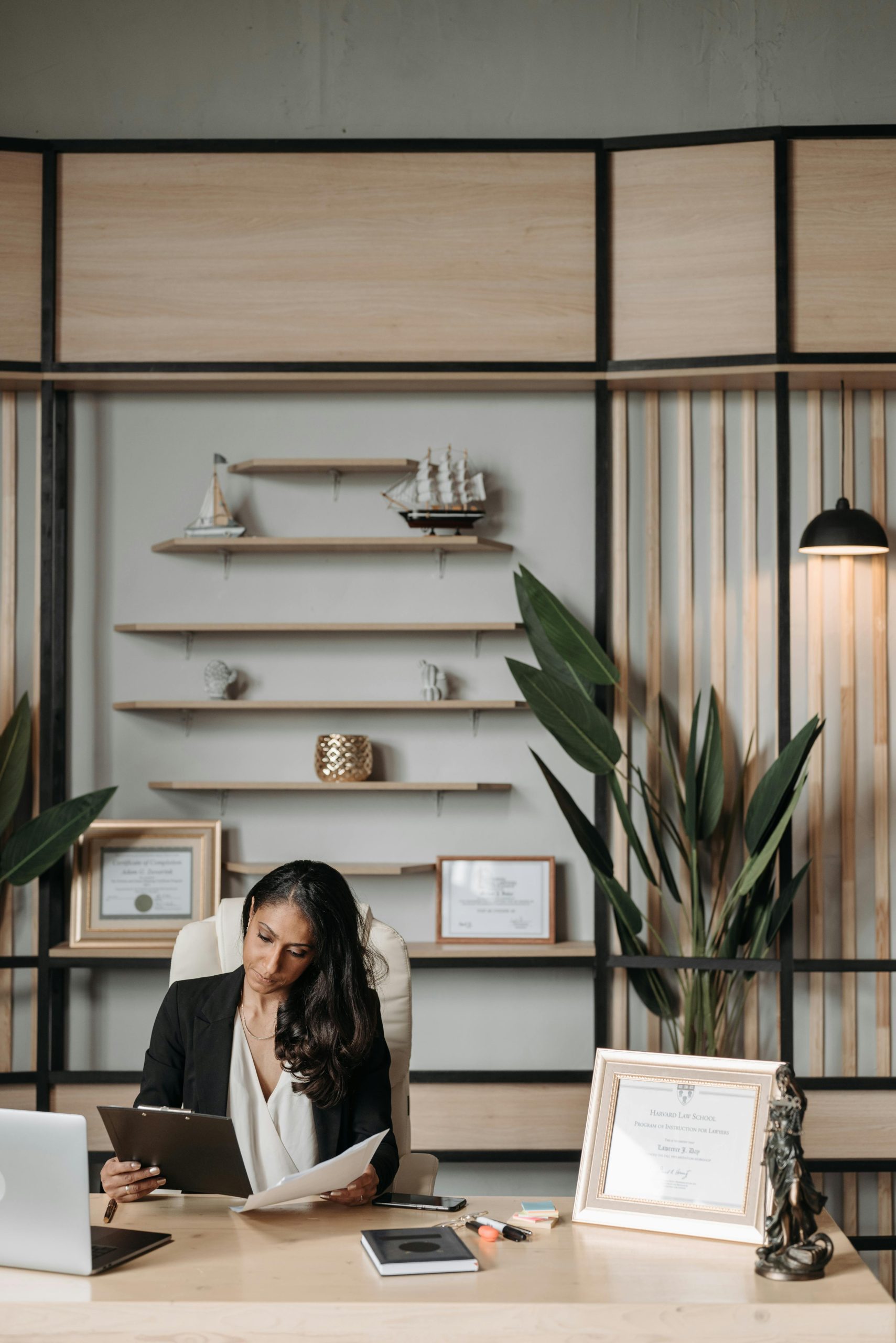 Confident female CEO reviews paperwork at elegant desk in a modern office setting. Professional and thoughtful.